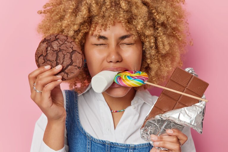 Woman with sweets—cookie, lollipop, marshmallow, chocolate—highlighting sugar addiction.